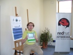 Community member with OLPC, Fedora and Red Hat posters in the background
